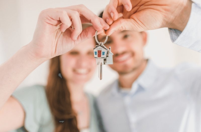 Image is showing a happy couple holding the keys to their new home.