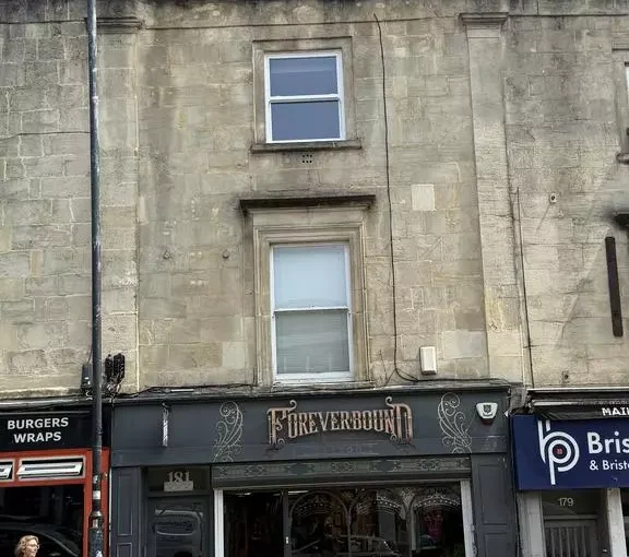 Stone-fronted period building on a high street, with a shop called "Foreverbound" on the ground floor and two residential windows above.